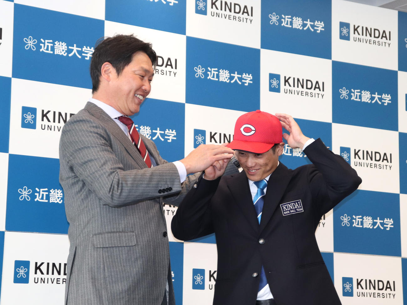指名あいさつに訪れた広島・新井貴浩監督に球団の帽子をかぶせてもらった、同3位の近大・勝田（撮影・中島麗）