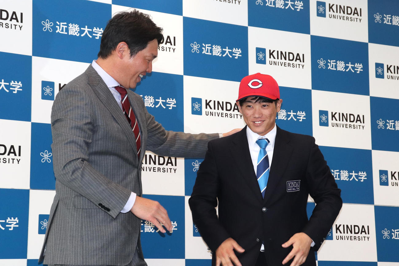 指名あいさつに訪れた広島・新井貴浩監督に球団の帽子をかぶせてもらった、同3位の近大・勝田（撮影・中島麗）