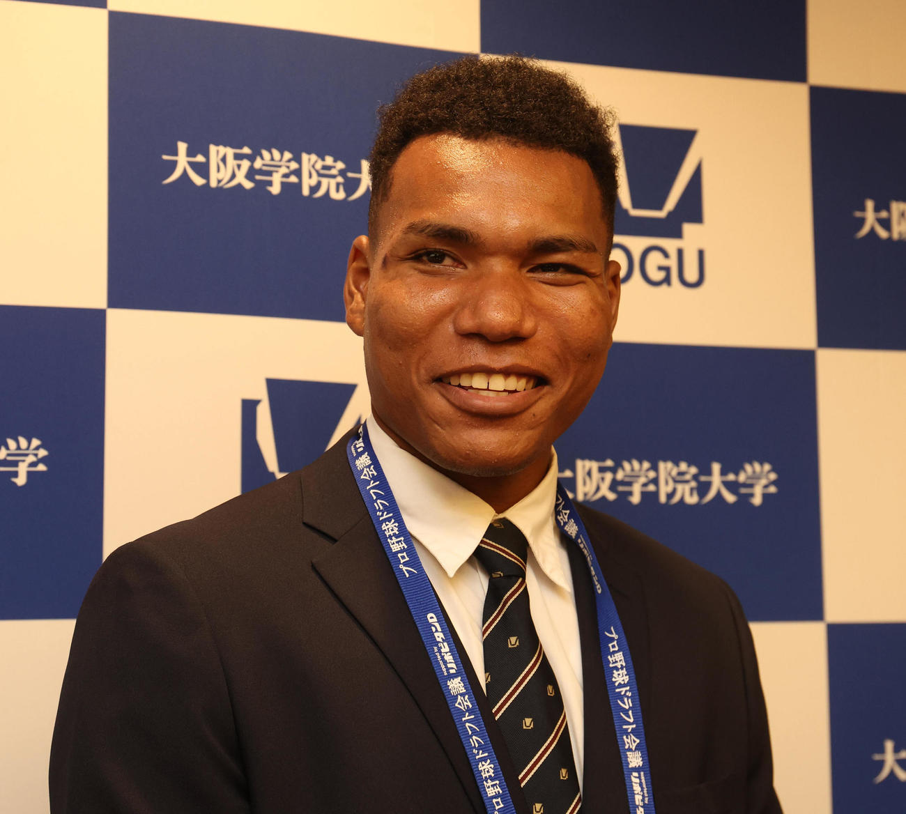 日本ハムからの指名あいさつを終えて囲み取材を受け笑顔を見せる大阪学院大エドポロ　ケイン（撮影・白石智彦）