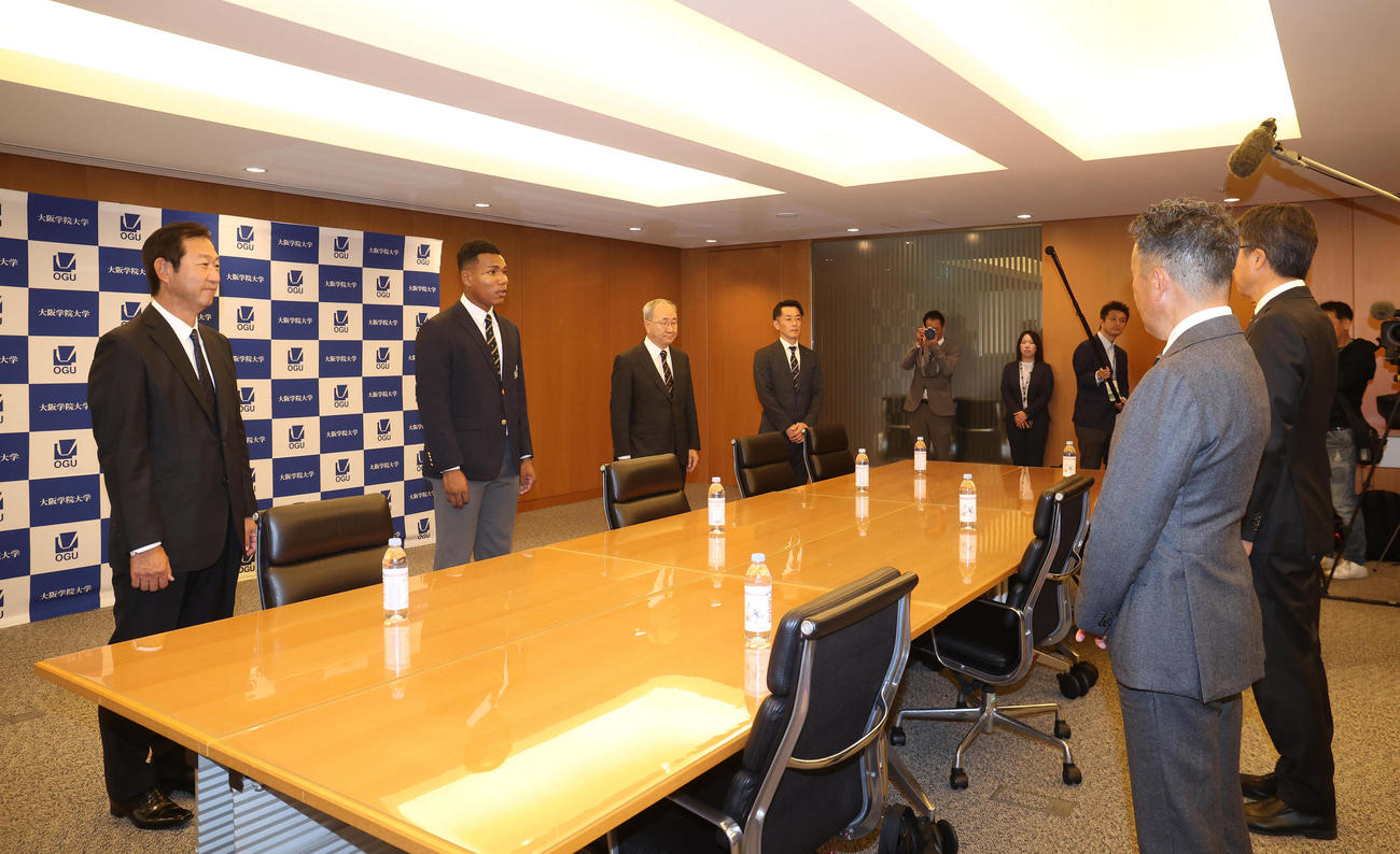 日本ハムからの指名あいさつを受ける、左列手前から大阪学院大中村良二監督、エドポロ　ケイン、三輪信哉部長。右列手前から日本ハム熊崎誠也スカウト、大渕隆スカウト部長（撮影・白石智彦）