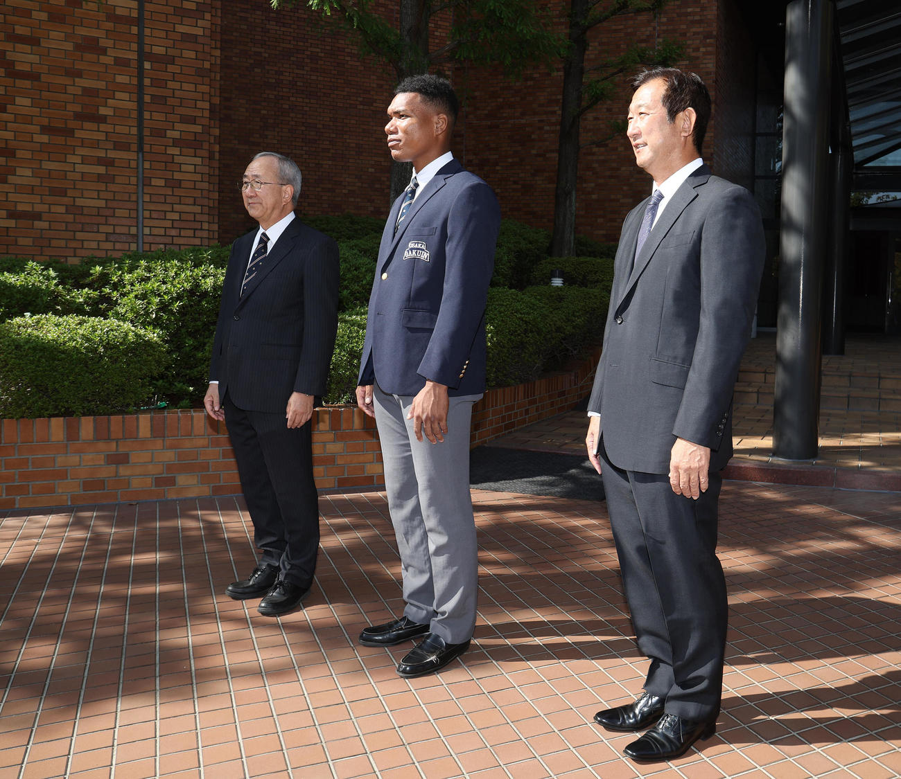 日本ハムスカウト陣を出迎える、左から大阪学院大硬式野球部三輪信哉部長、エドポロ　ケイン、中村良二監督（撮影・白石智彦）