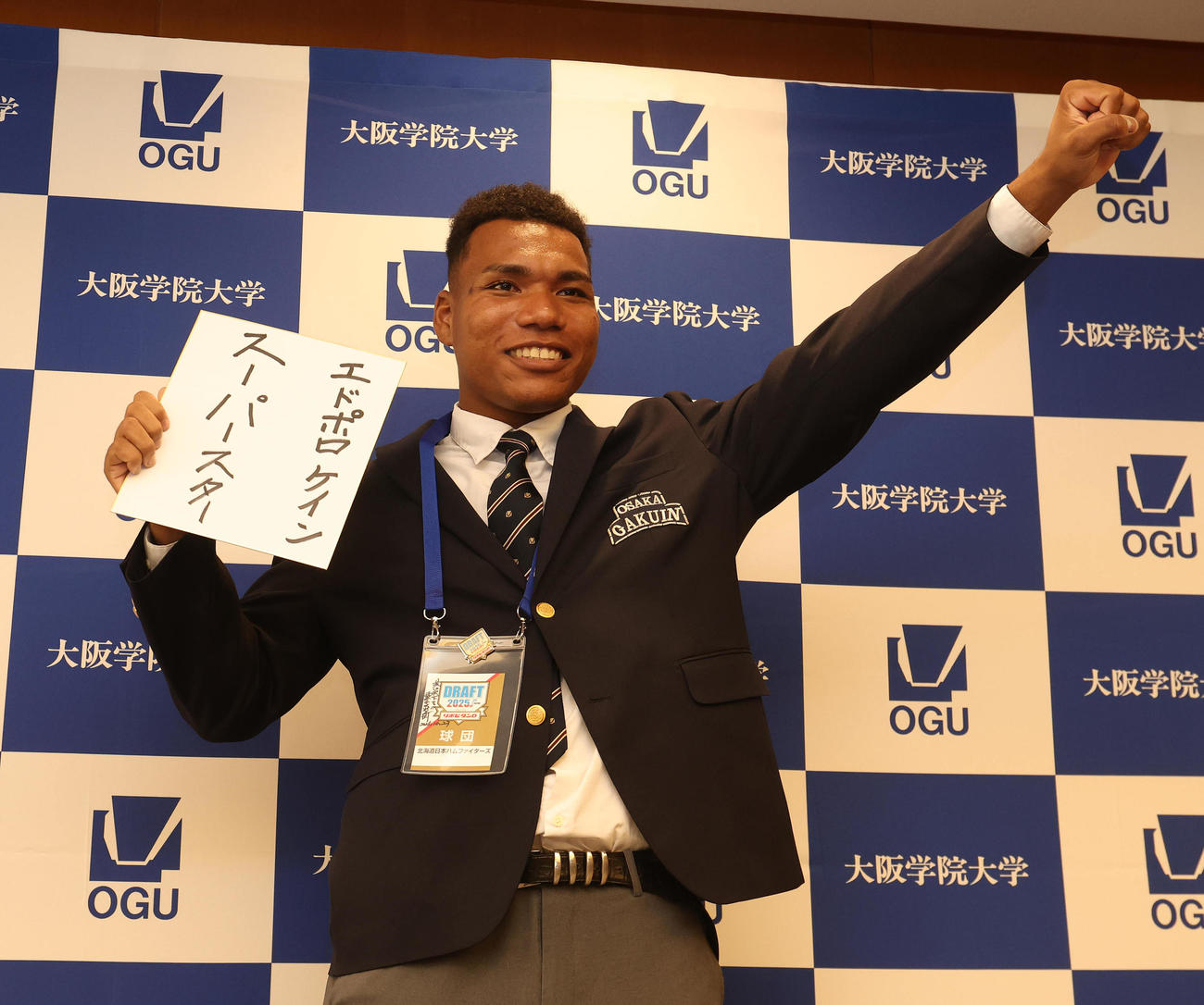 スーパースターと書かれた色紙を手にガッツポーズする大阪学院大エドポロ　ケイン（撮影・白石智彦）