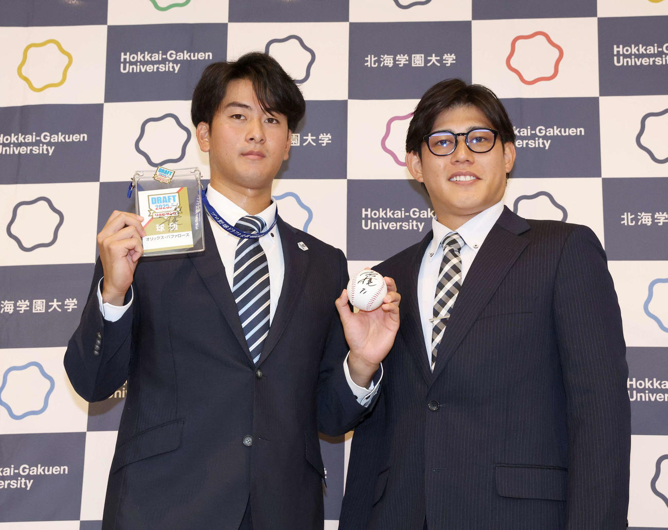 オリックスから5位指名された北海学園大の高谷（左）は佐野アマチュアスカウトから指名あいさつをうけ笑顔（撮影・黒川智章）
