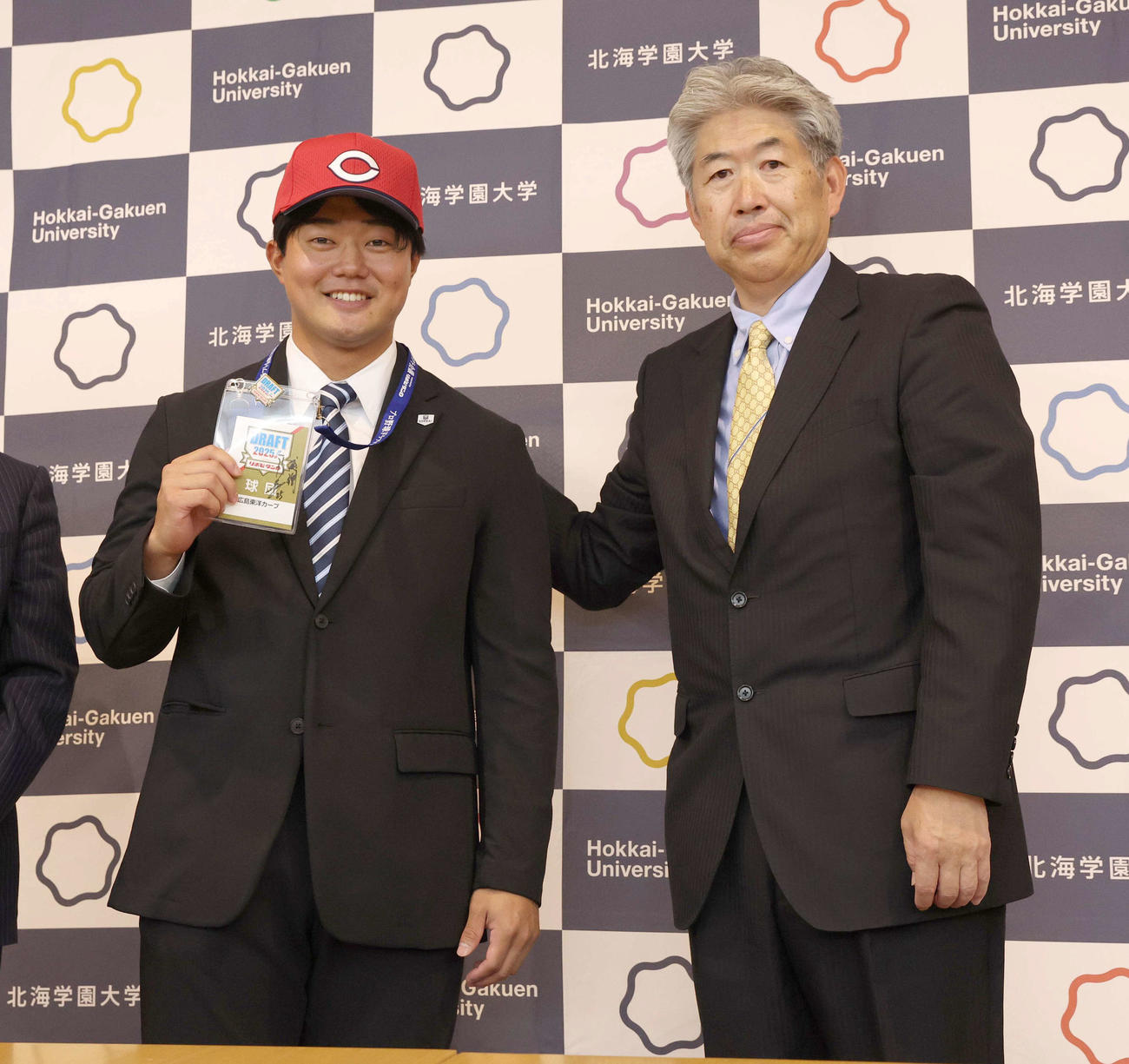 広島から4位指名された北海学園大の工藤（左）は近藤スカウトから指名あいさつをうけ笑顔を見せる（撮影・黒川智章）