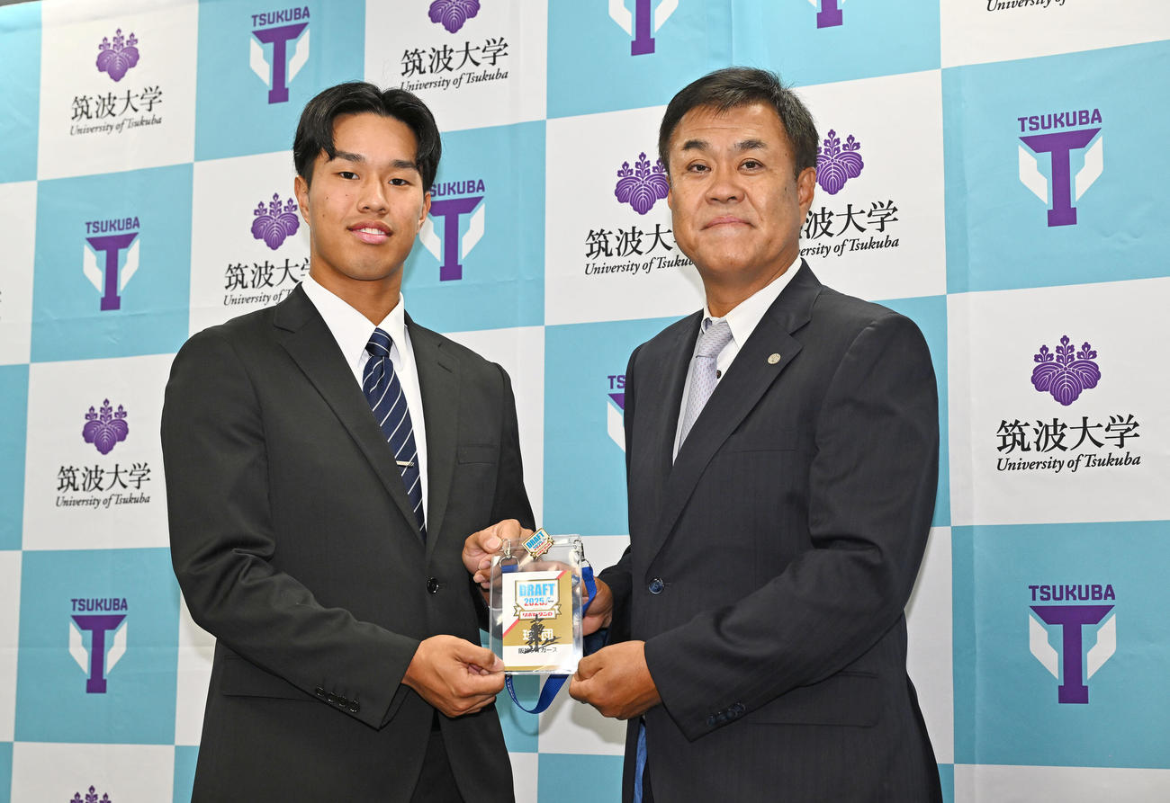 指名あいさつを受けた阪神ドラフト3位の筑波大・岡城（左）は平塚スカウトから藤川監督のサイン入りドラフト会議のパスを受け取る（撮影・滝沢徹郎）