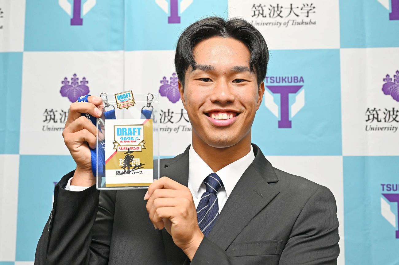 指名あいさつを受けた阪神ドラフト3位の筑波大・岡城は藤川監督のサイン入りドラフト会議のパスを受け取り笑顔を見せる（撮影・滝沢徹郎）