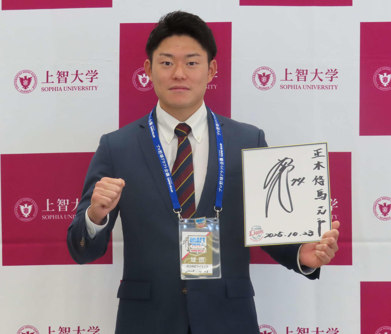 西武西口監督の直筆サインが入ったパスと色紙を受け取りガッツポーズをする上智大・正木（撮影・山本佳央）