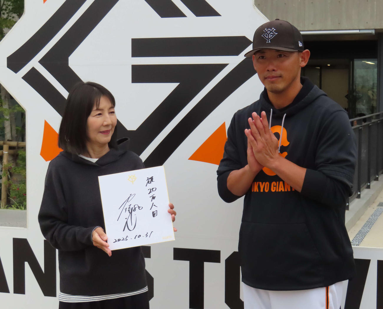 ジャイアンツタウンスタジアム来場20万人目の来場者にサイン色紙を贈呈した矢野巡回打撃コーチ（撮影・水谷京裕）