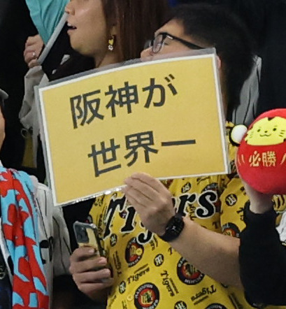 2025年3月16日、阪神対ドジャース　7回裏の攻撃を前に、六甲おろしが流れる中、「阪神が世界一」ボードを掲げるファン