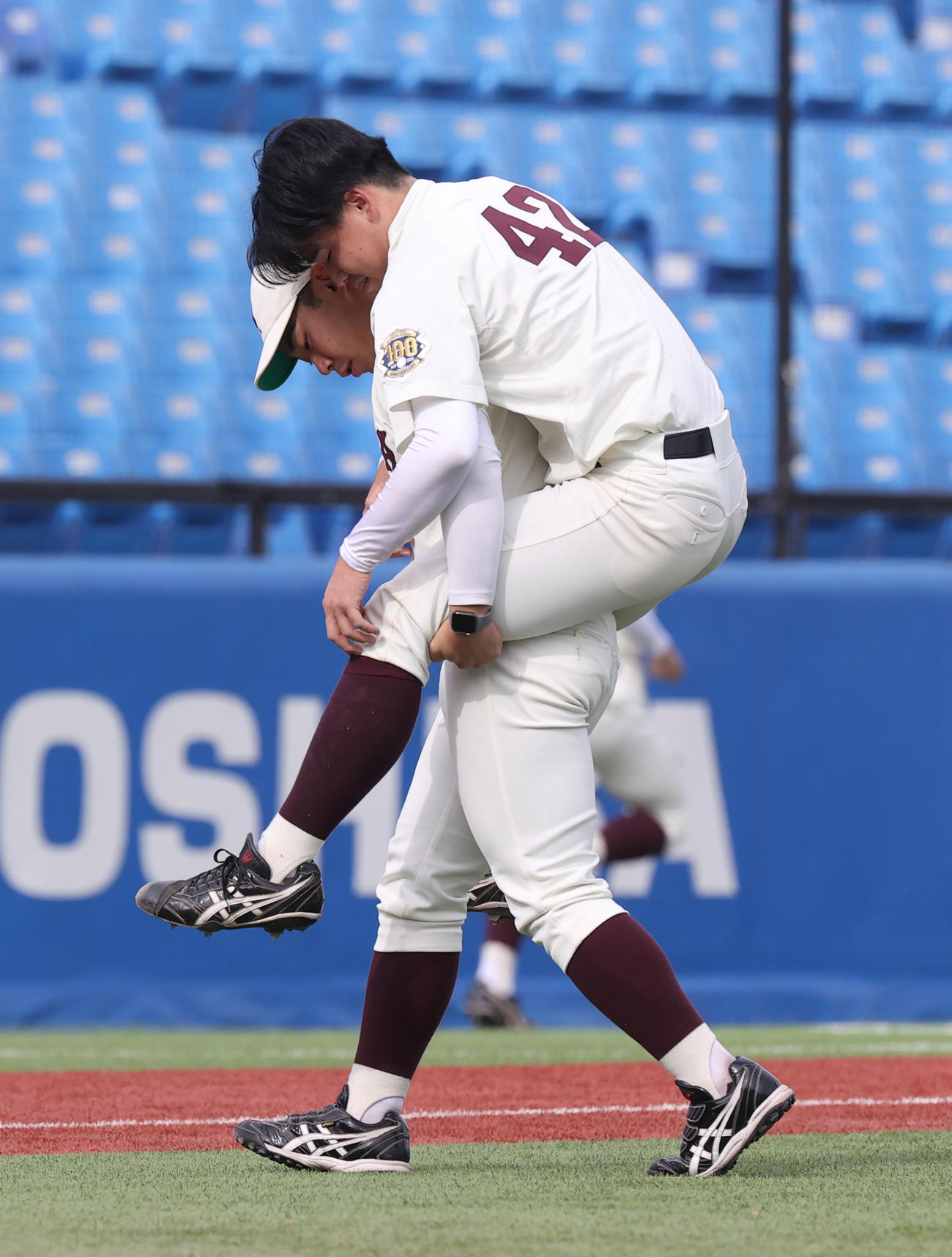 早大対慶大　1回裏慶大2死、市橋の打球が当たりおんぶされベンチに引き揚げる早大・佐宗（撮影・柴田隆二）