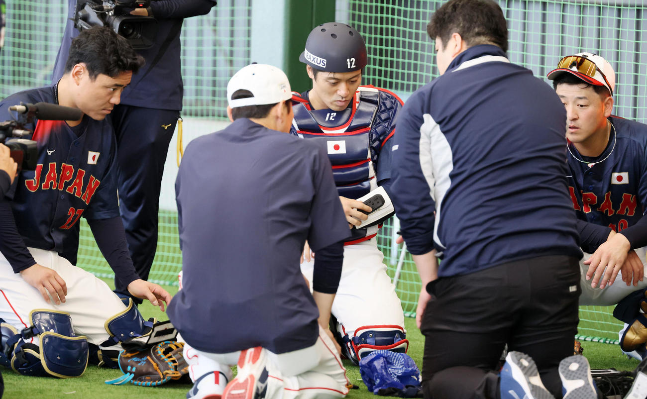 ブルペンでピッチコムの器具を装着してみる坂本。左は中村、右は岸田（撮影・加藤哉）