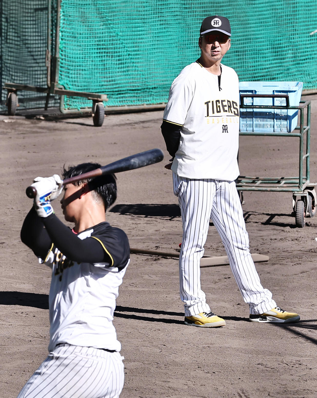 トス打撃を行う阪神百崎（手前）を見つめる藤川監督（撮影・上山淳一）