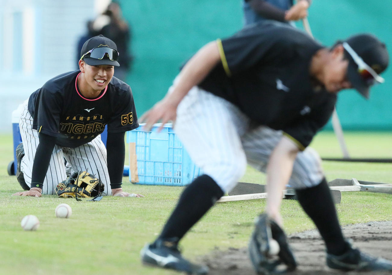 阪神平田2軍監督の連続ノックの合間に座り込む百崎。手前は川崎（撮影・上山淳一）