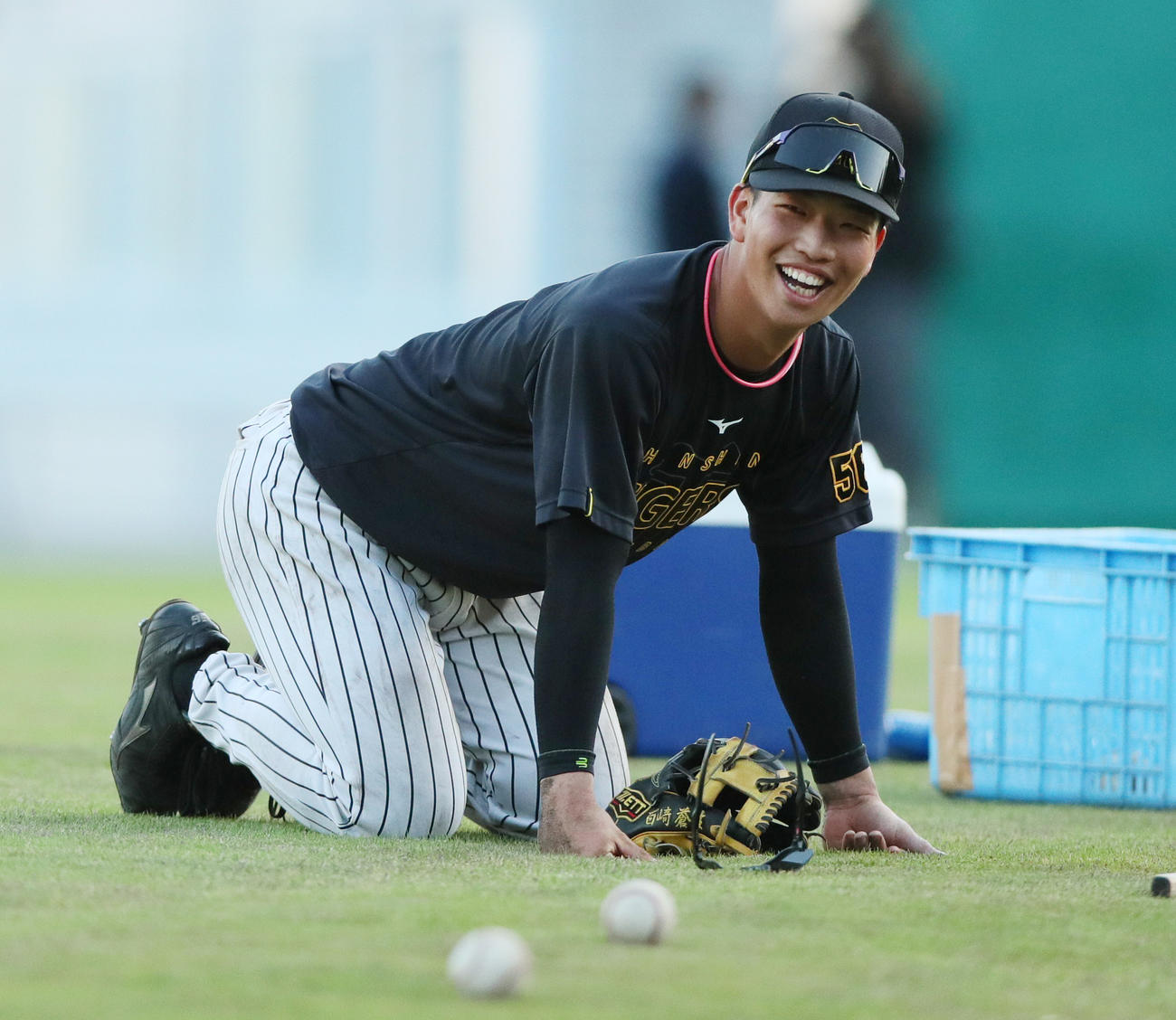 阪神平田2軍監督の連続ノックの合間に座り込み笑顔を見せる百崎（撮影・上山淳一）