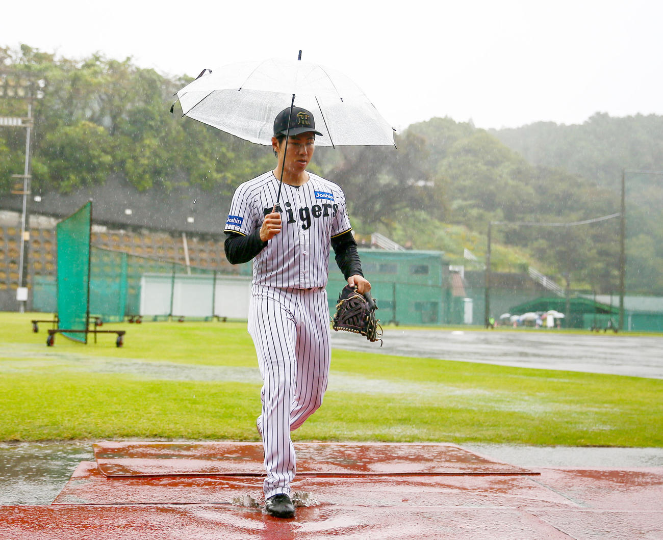 傘を差してグラウンドを移動する阪神工藤（撮影・上山淳一）