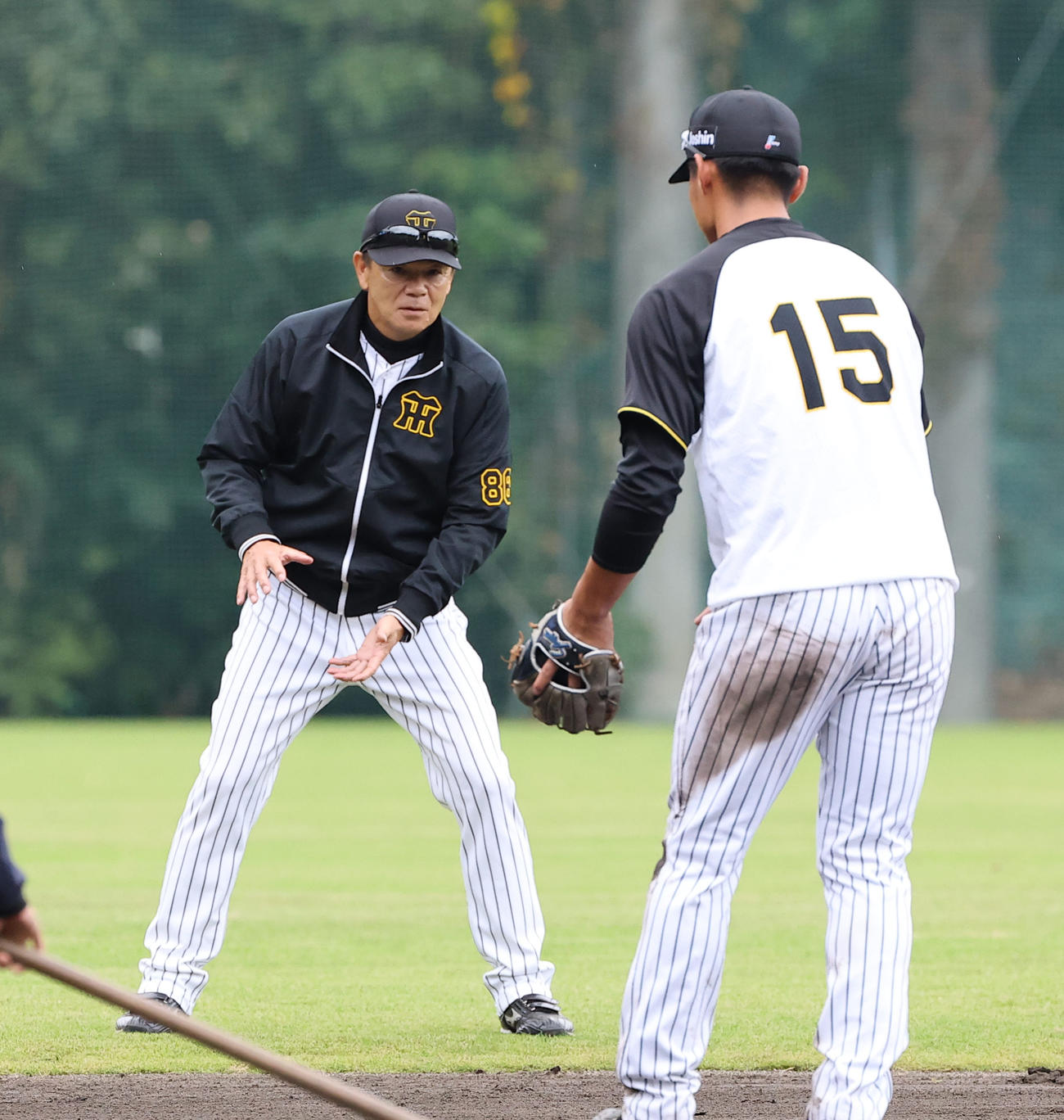 内野ノックを受ける西純（右）を指導する和田ヘッドコーチ（撮影・上田博志）