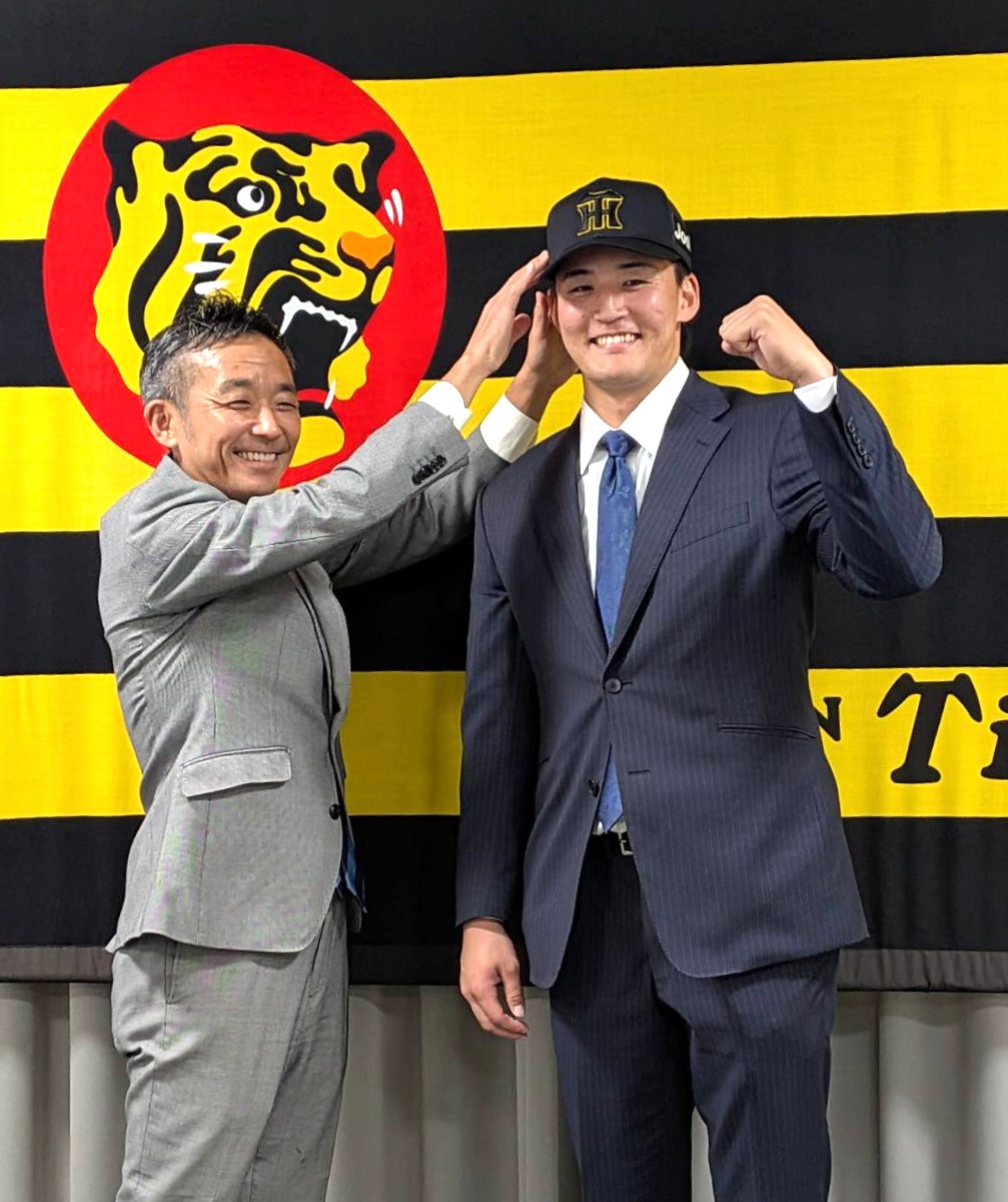 入団会見で竹内球団副本部長に帽子をかぶせてもらう阪神元山（撮影・柏原誠）
