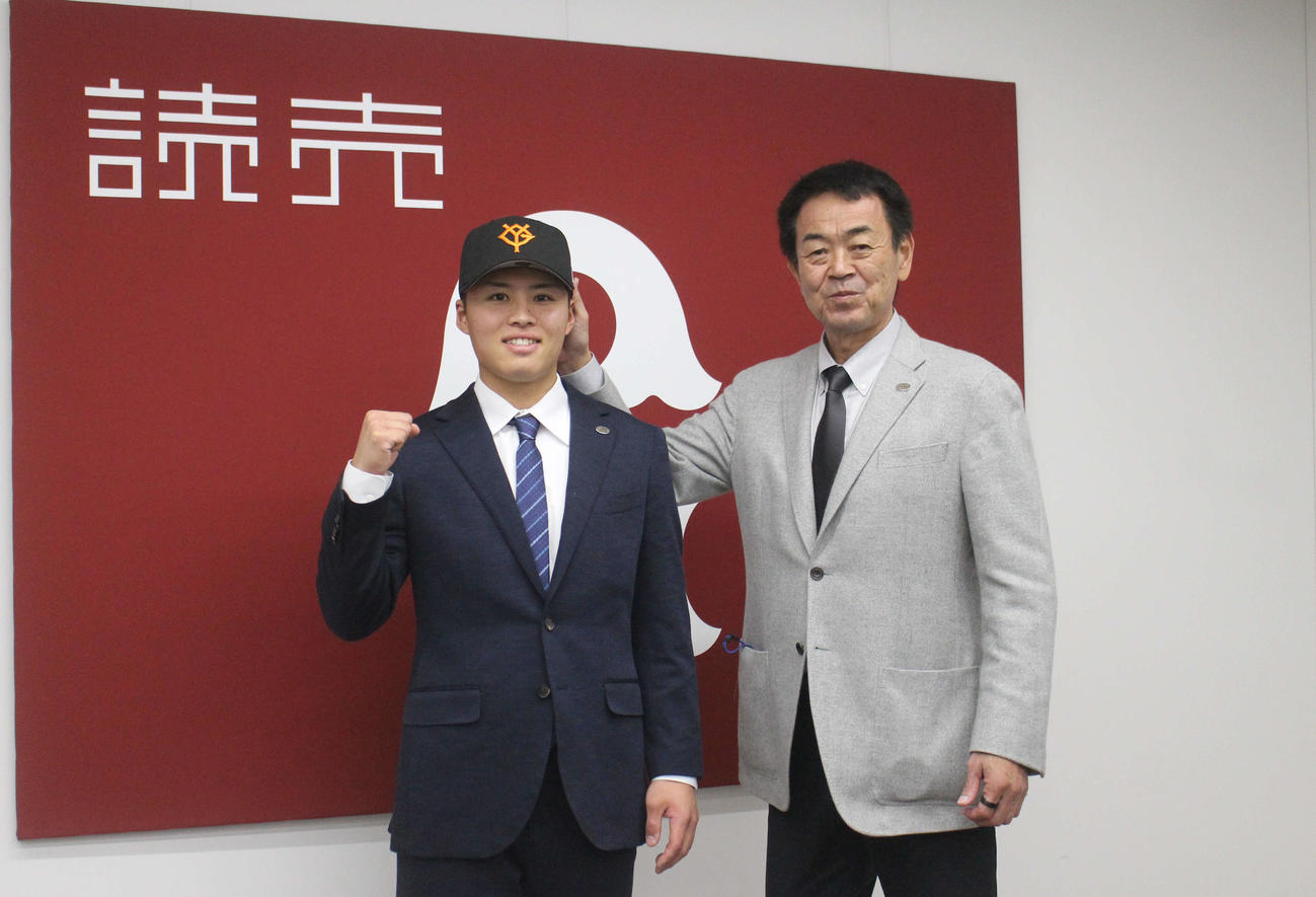 巨人帽子を被って意気込みを語る川原田。右は水野編成本部長