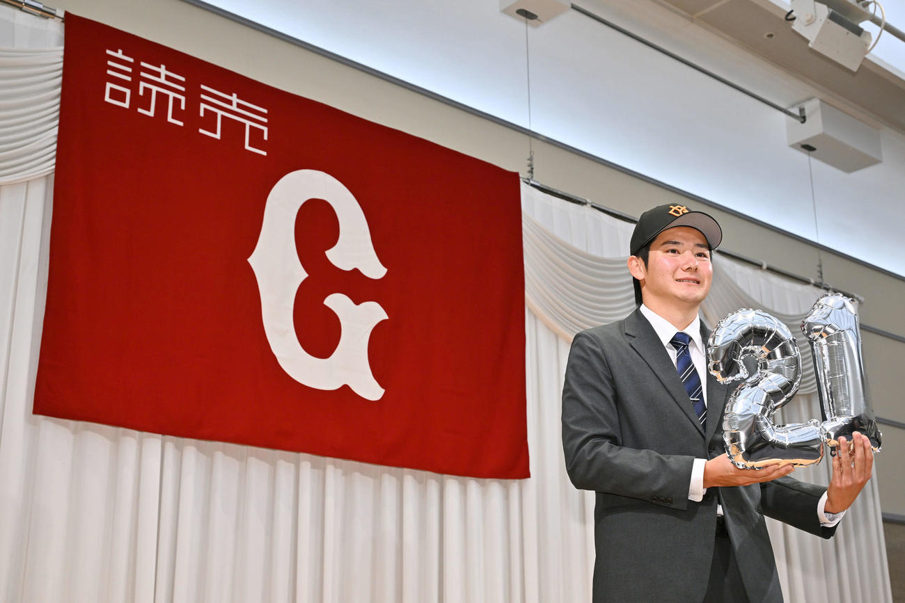 仮契約を終えた巨人ドラフト1位の鷺宮製作所・竹丸は決まった背番号「21」のバルーンを手に写真に納まる（撮影・滝沢徹郎）