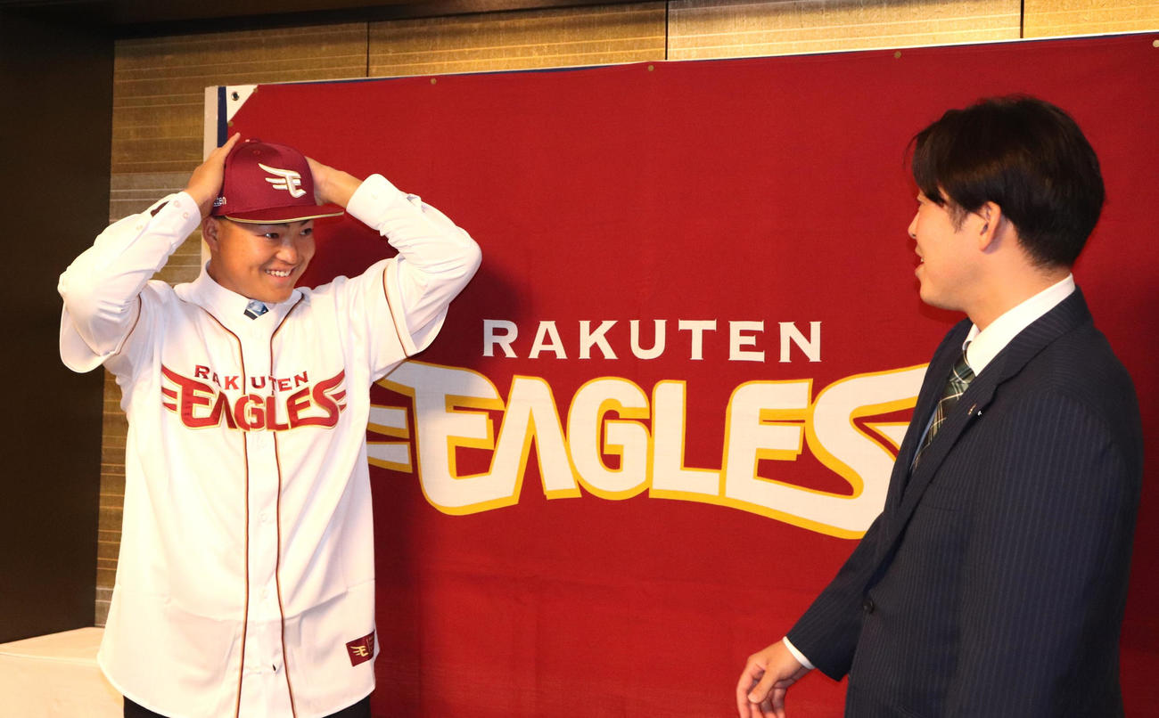 楽天と契約合意し、担当の足立スカウトにユニホームを着せてもらったドラフト7位の近大・阪上（撮影・中島麗）