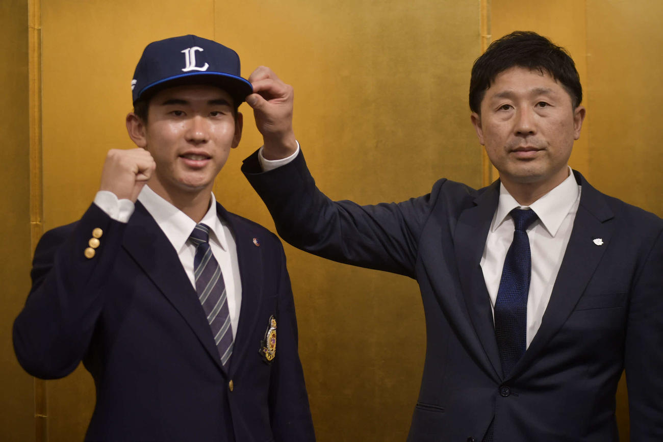 西武の帽子をかぶるドラフト1位明大・小島（左）と担当の阿部スカウト（撮影・平山連）