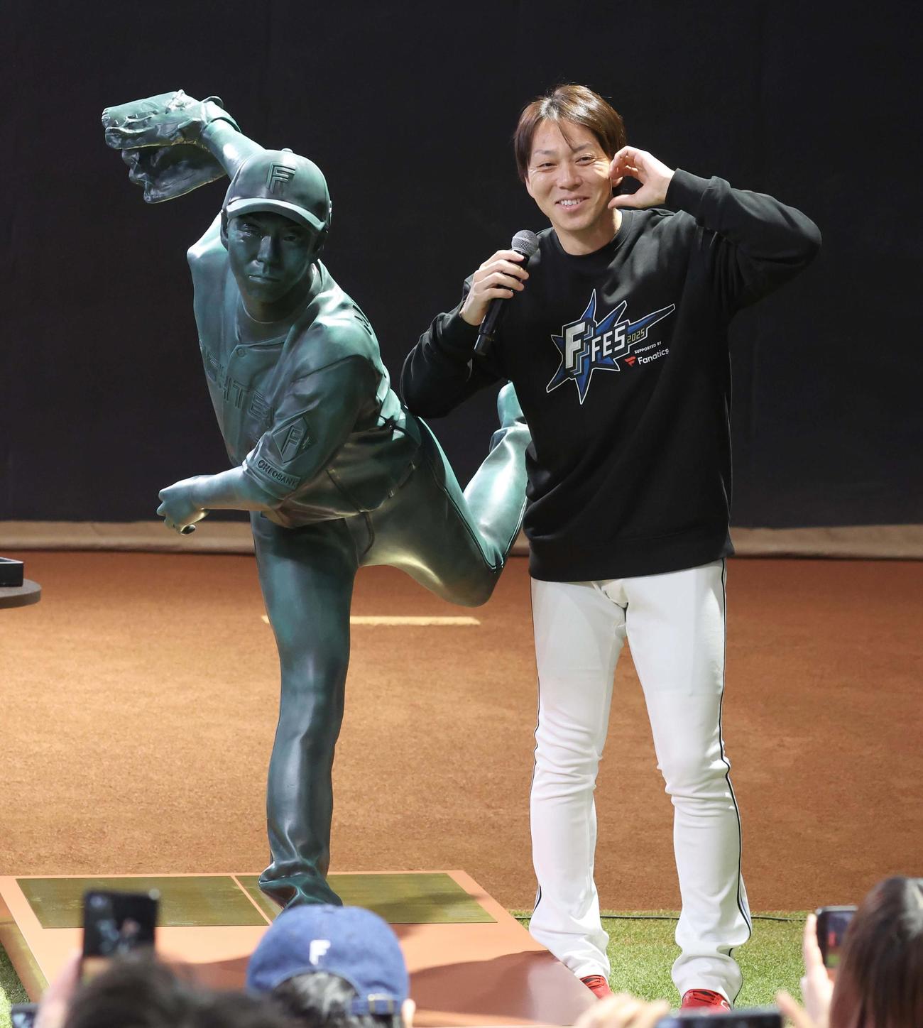 自身の銅像の横でポーズをとる宮西（撮影・黒川智章）