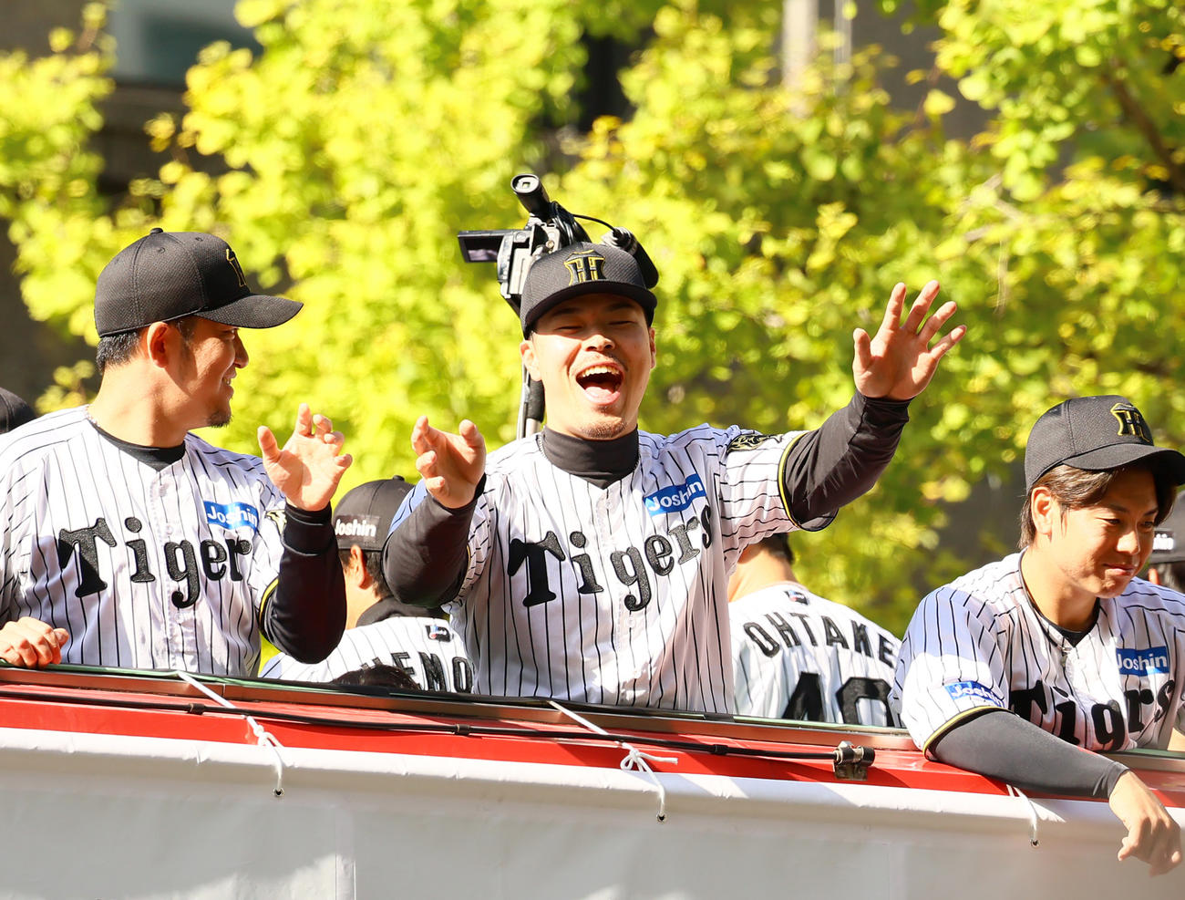 優勝パレードでファンに手を振る阪神佐藤輝（中央）、左は岩貞、〓（上白矢印）は梅野（撮影・上山淳一）