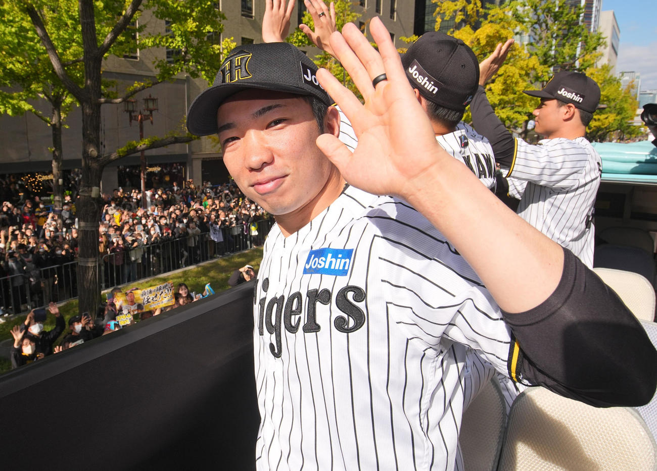 阪神優勝パレードでカメラに手を振る石井大智＝22日午前、大阪市中央区（代表撮影）
