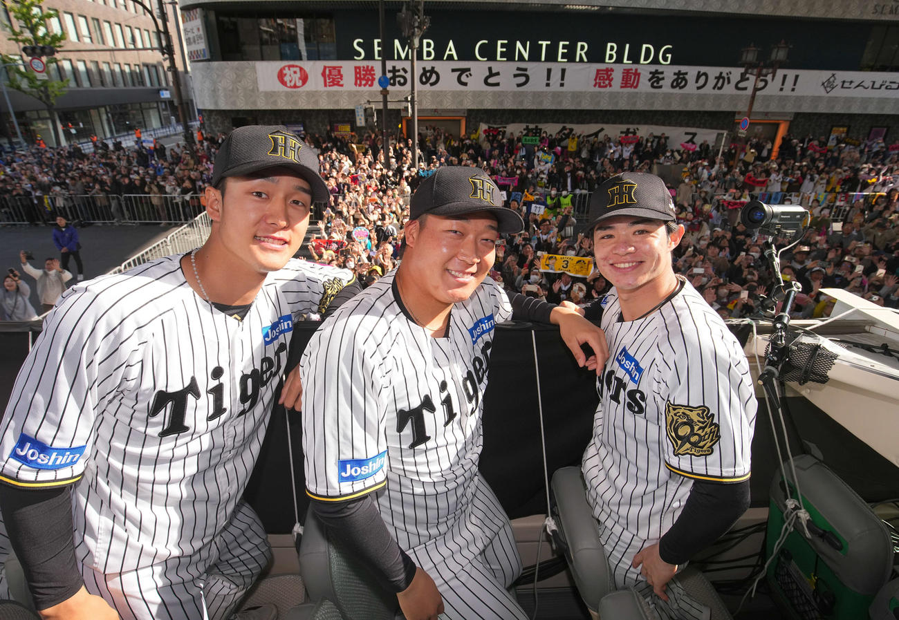 阪神優勝パレードで、船場センタービル前に集まった大勢のファンをバックに笑顔をみせる（左から）阪神小幡、大山、中野（代表撮影）