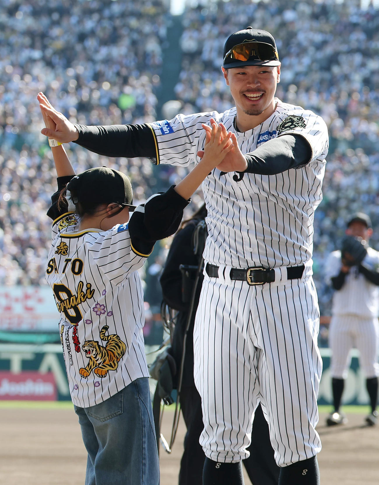 夢を叶えたファンの少女とタッチを交わす阪神佐藤輝（撮影・前田充）