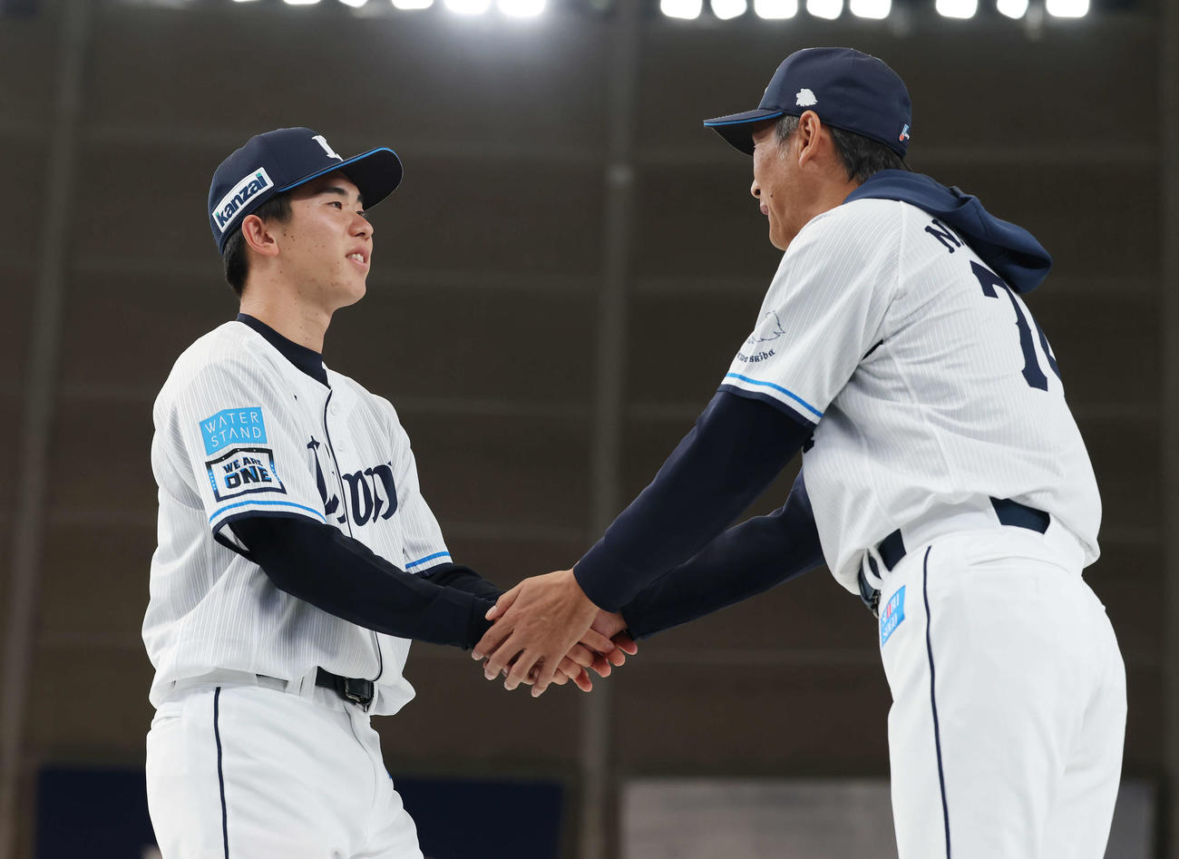 西武ファン感謝イベント「LIONS THANKS FESTA 2025」の新入団選手発表会で西口監督（右）と握手するドラフト1位小島（撮影・宮地輝）