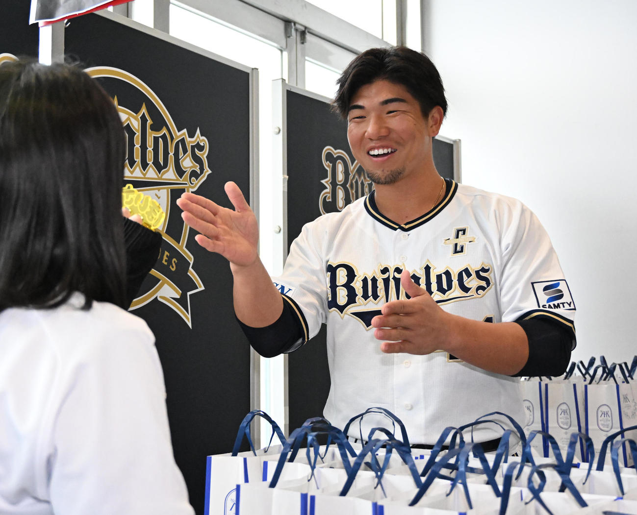 来場者にプリンを手渡しほいさーをする頓宮（撮影・石井愛子）