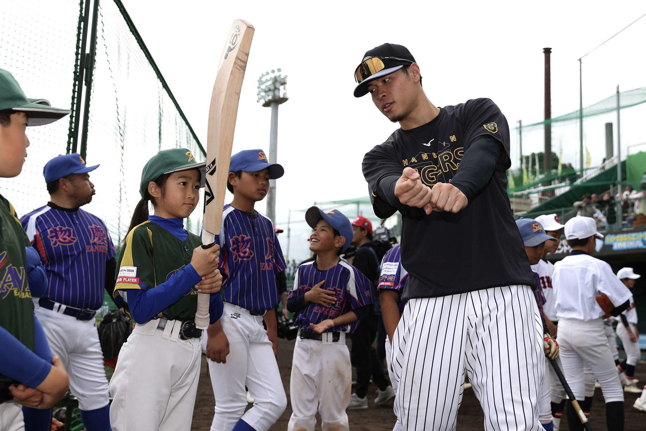 2月11日、春季キャンプの野球教室でクリケットバットを使って子どもたちを指導する阪神佐藤