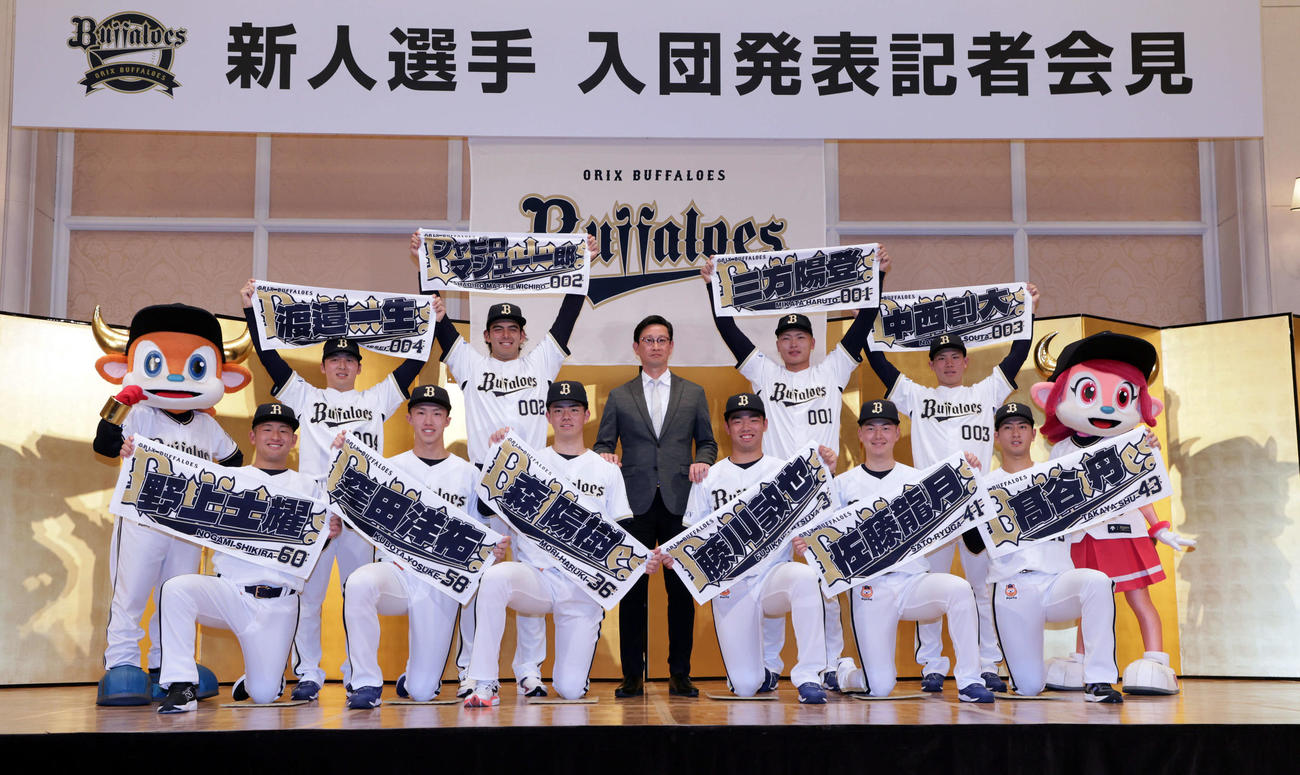 岸田護監督（中央）を囲み、それぞれのネームタオルを掲げるオリックスの新人選手たち。前列左から野上士耀、窪田洋祐、森陽樹、藤川敦也、佐藤龍月、高谷舟。後列左から渡辺一生、シャピロ・マシュー・一郎、三方陽登、中西創大（撮影・宮崎幸一)