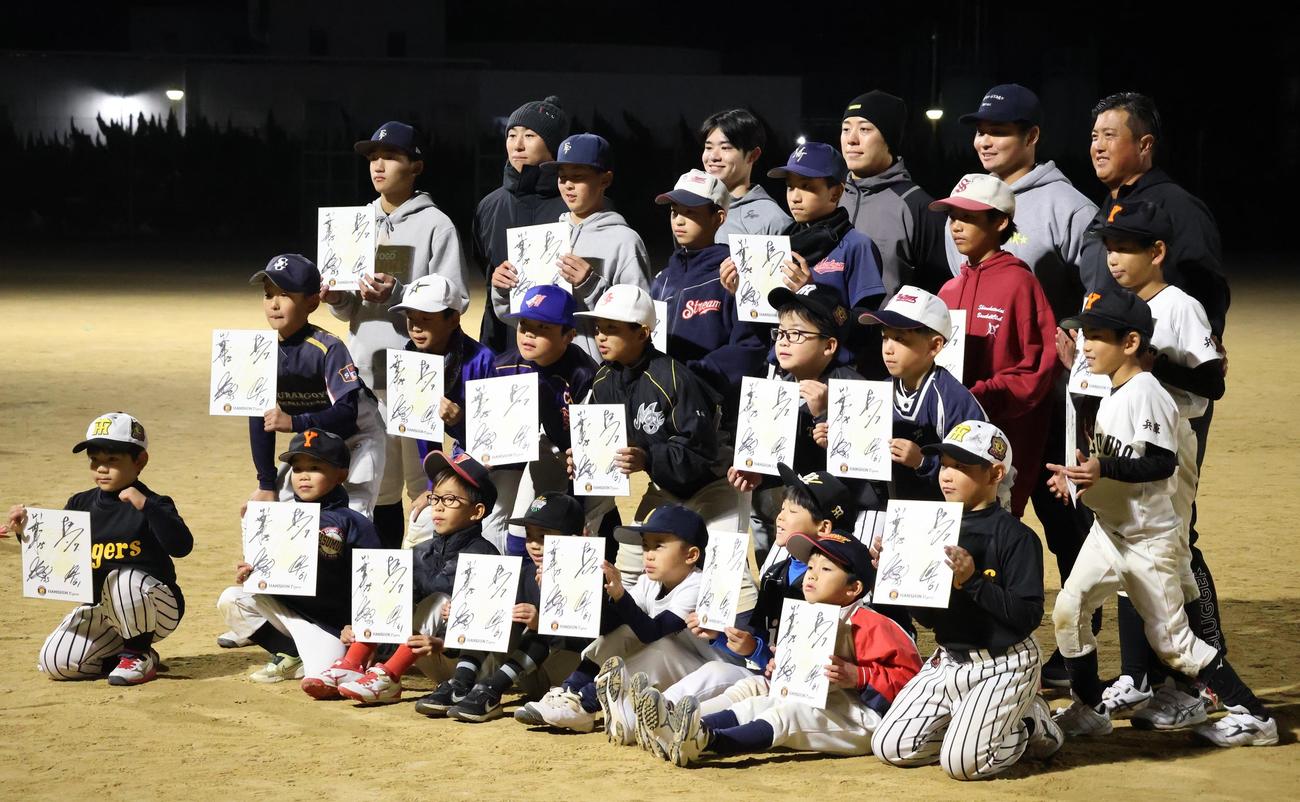 野球教室後にサイン色紙を持った子どもたちと記念撮影を行う、右から阪神松原、豊田、中野、山崎2軍内野守備走塁コーチ（撮影・塚本光）