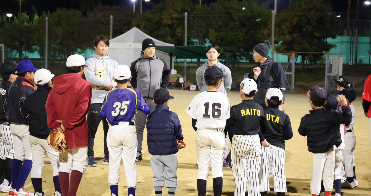 野球教室で子どもたちの前に立つ、左から阪神松原、豊田、中野、山崎2軍内野守備走塁コーチ（撮影・塚本光）