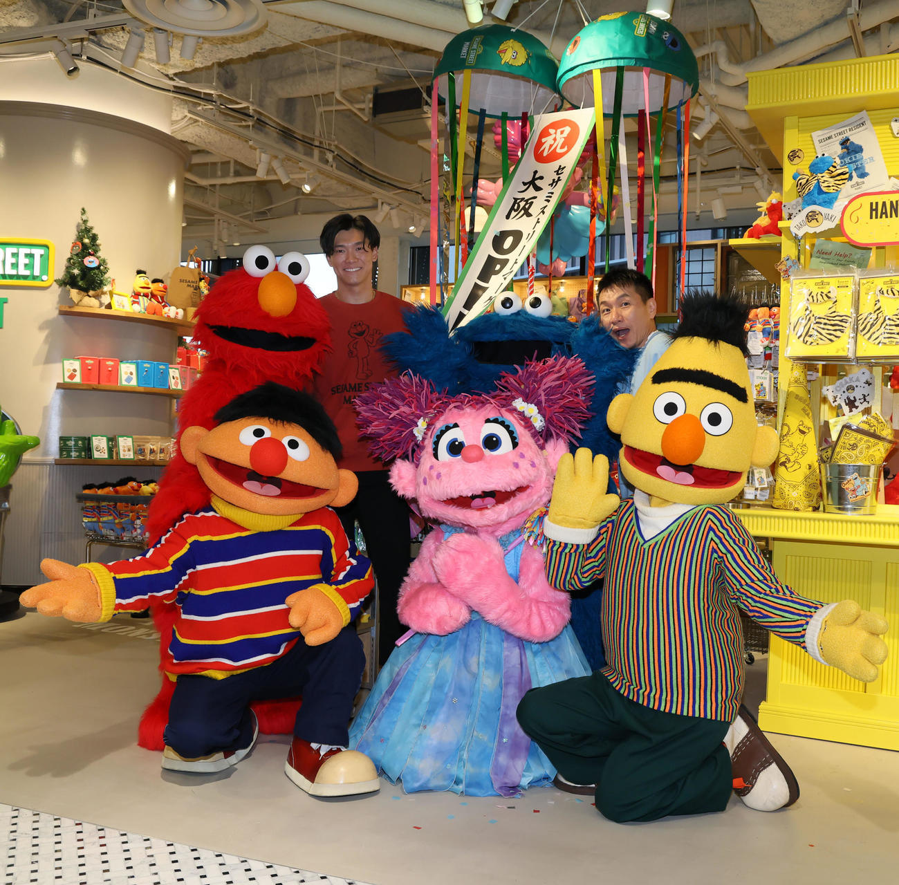 阪神梅田本店にセサミストリートマーケットがオープンし記念セレモニーで写真に納まる湯浅（左）とますだおかだの増田。前列左からはアーニー、アビー、バート、後列左からエルモ、ひとりおいてクッキーモンスター（撮影・加藤哉）
