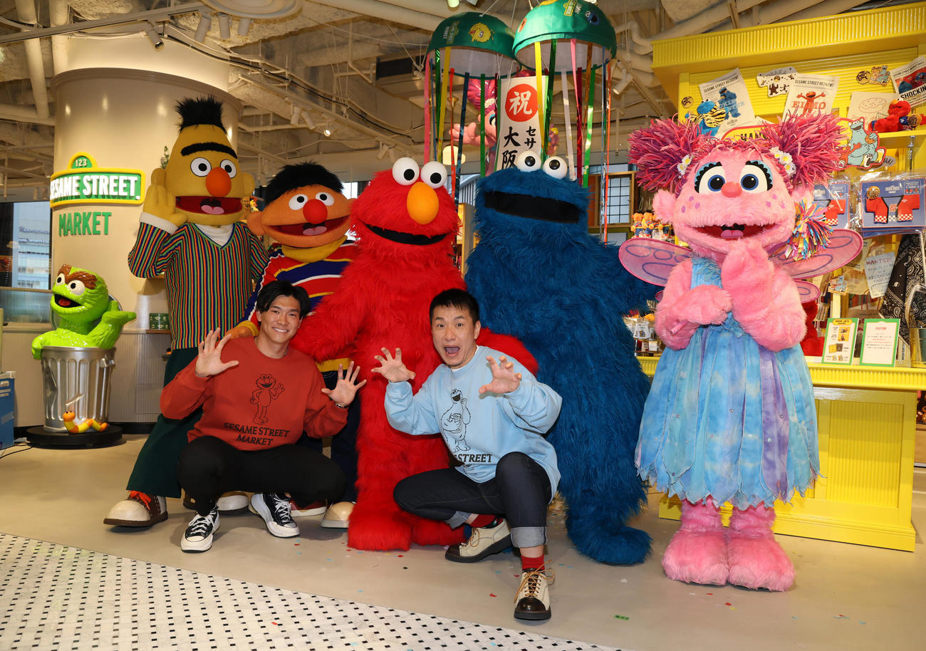 阪神梅田本店にセサミストリートマーケットがオープンし記念セレモニーでキャラクターたちと写真に納まる阪神湯浅（左）とますだおかだ増田。後列左からバート、アーニー、エルモ、クッキーモンスター、アビー（撮影・加藤哉）