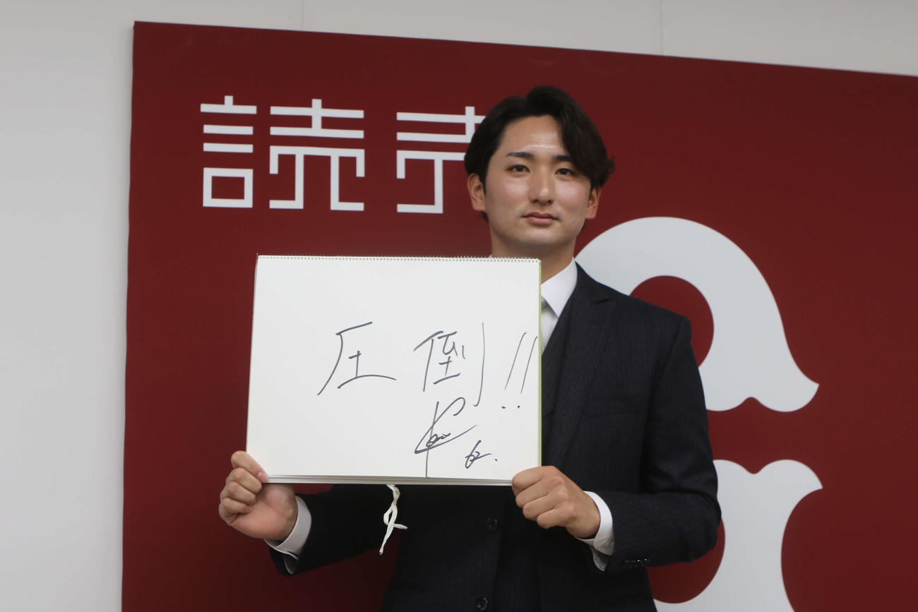 契約更改を終えた横川が色紙に「圧倒」と書いた
