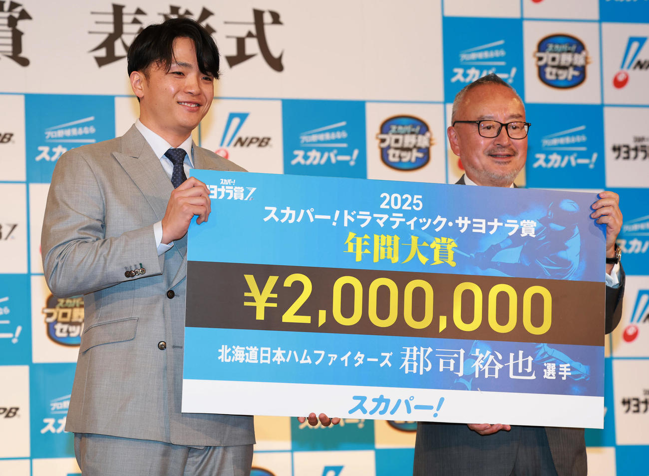 「2025　スカパー！ドラマティック・サヨナラ賞　年間大賞」を受賞し、スカパー！の米倉社長（右）から賞金200万円を贈られるパ・リーグの日本ハム郡司（撮影・野上伸悟）