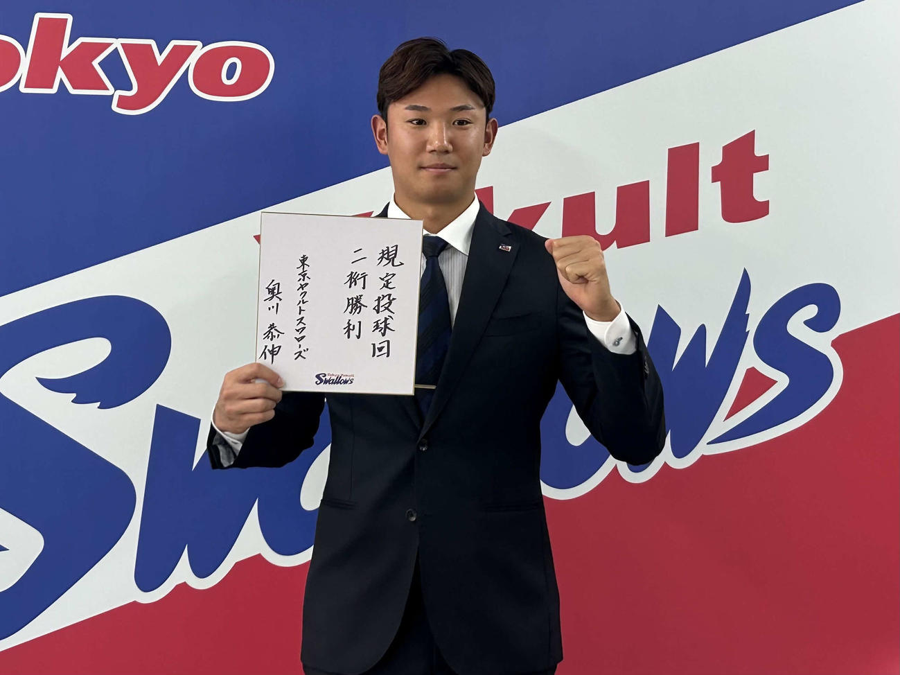 都内の球団事務所で契約更改に臨み来季の目標「規定投球回」「二桁勝利」を色紙に記しガッツポーズするヤクルト奥川