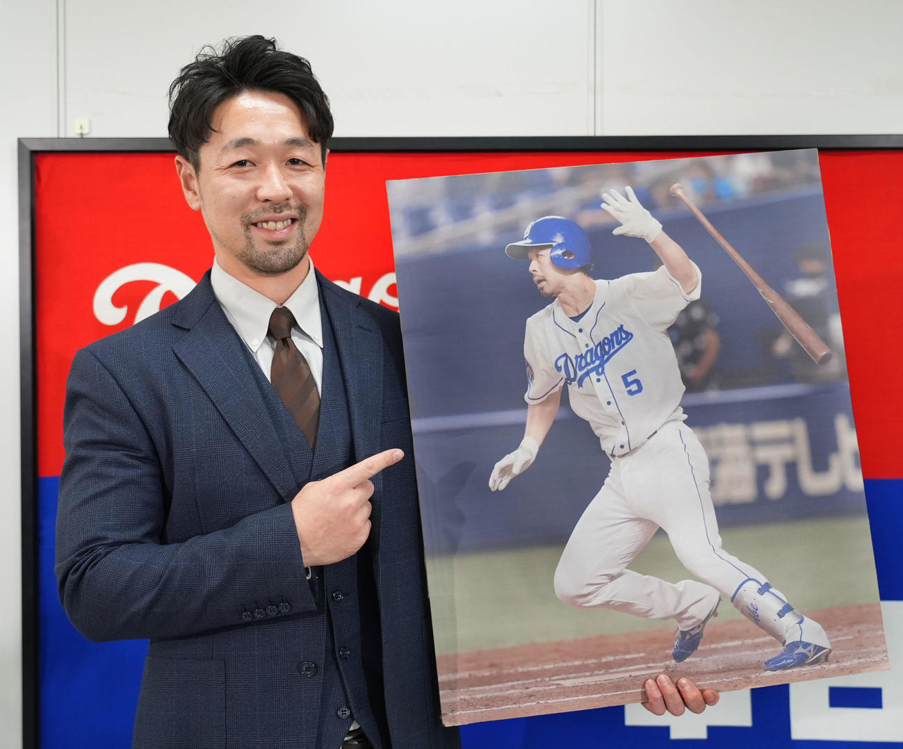 入団会見後、在籍時の写真パネルを手に笑顔を見せる阿部寿樹（撮影・森本幸一）