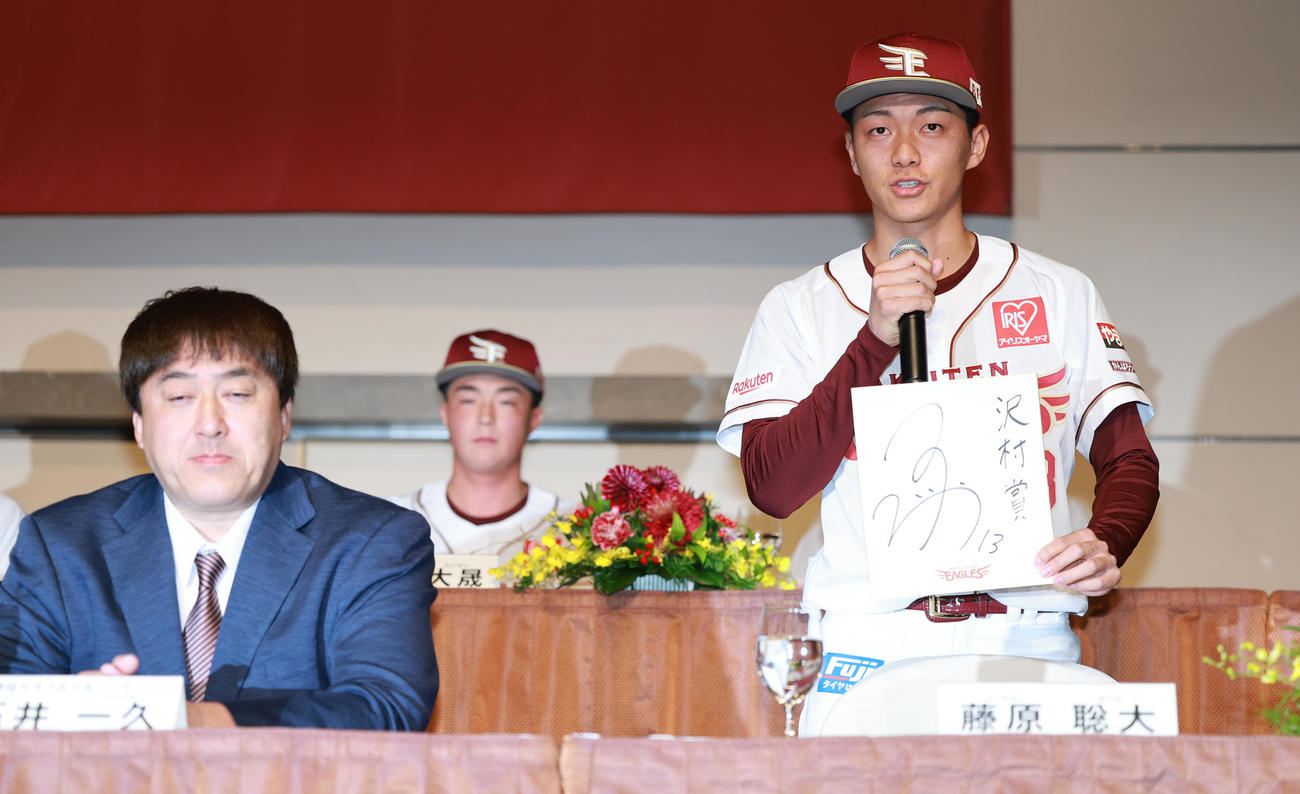 楽天新入団選手発表会見で色紙に沢村賞と記す楽天ドラフト1位の花園大・藤原。左は石井GM（撮影・野上伸悟）