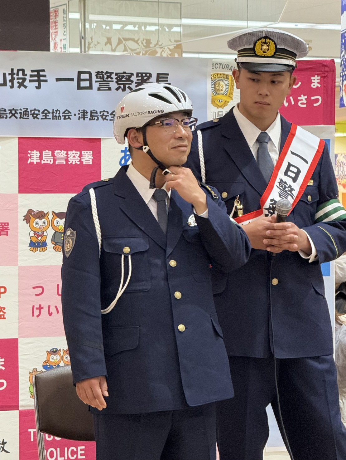 津島警察署の1日署長を務めた中日松山（右）は警察官からヘルメットの着用方法を学ぶ