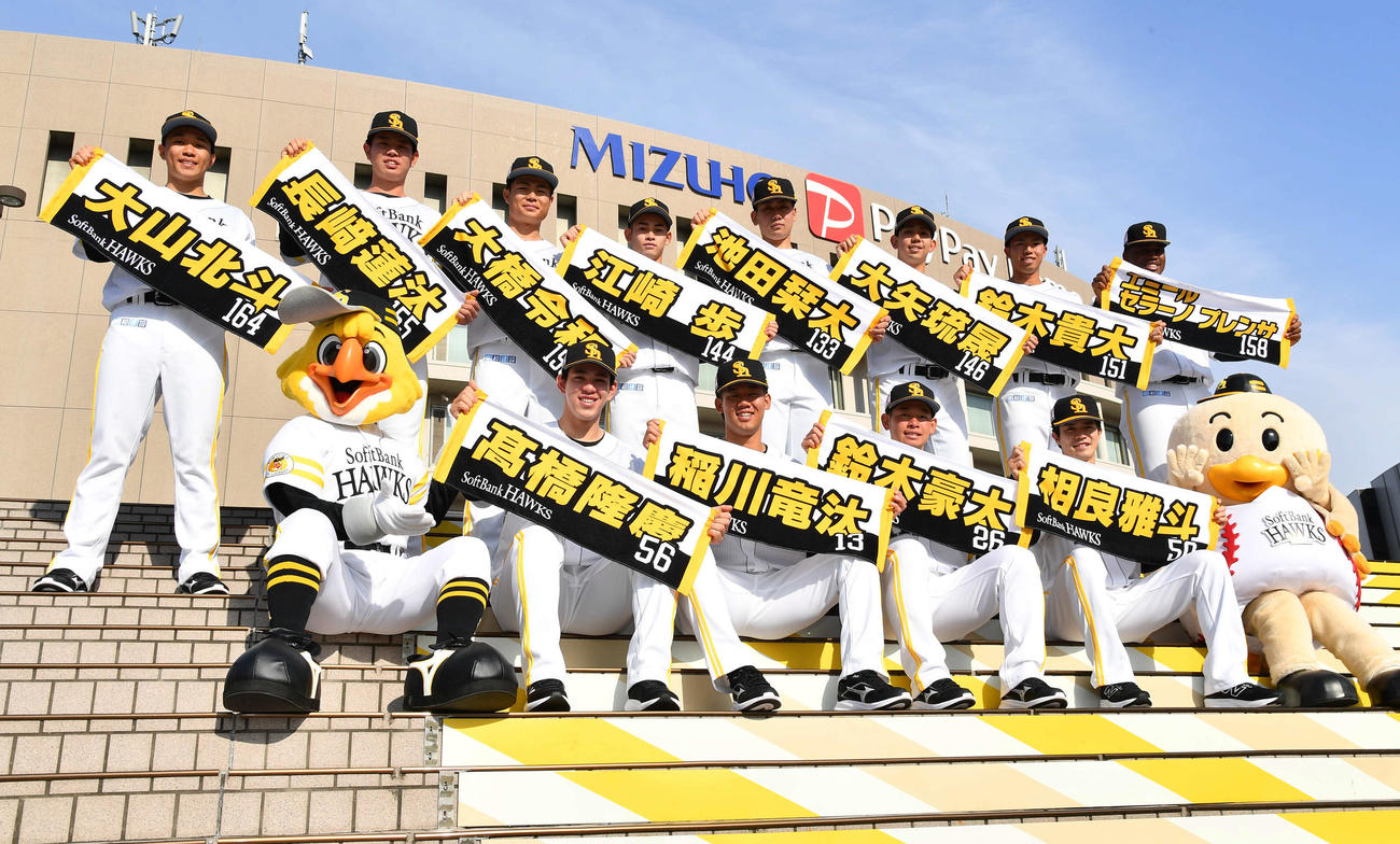 本拠地みずほペイペイドームを背に集合写真に納まる、前列左からソフトバンクドラフト5位・高橋、2位・稲川、3位・鈴木豪、4位・相良、後列左から育成8位・大山北、育成6位・長崎、育成4位大橋、育成2位・江崎、育成1位・池田、育成3位・大矢、育成5位・鈴木貴、育成7位・エミール（撮影・岩下翔太）