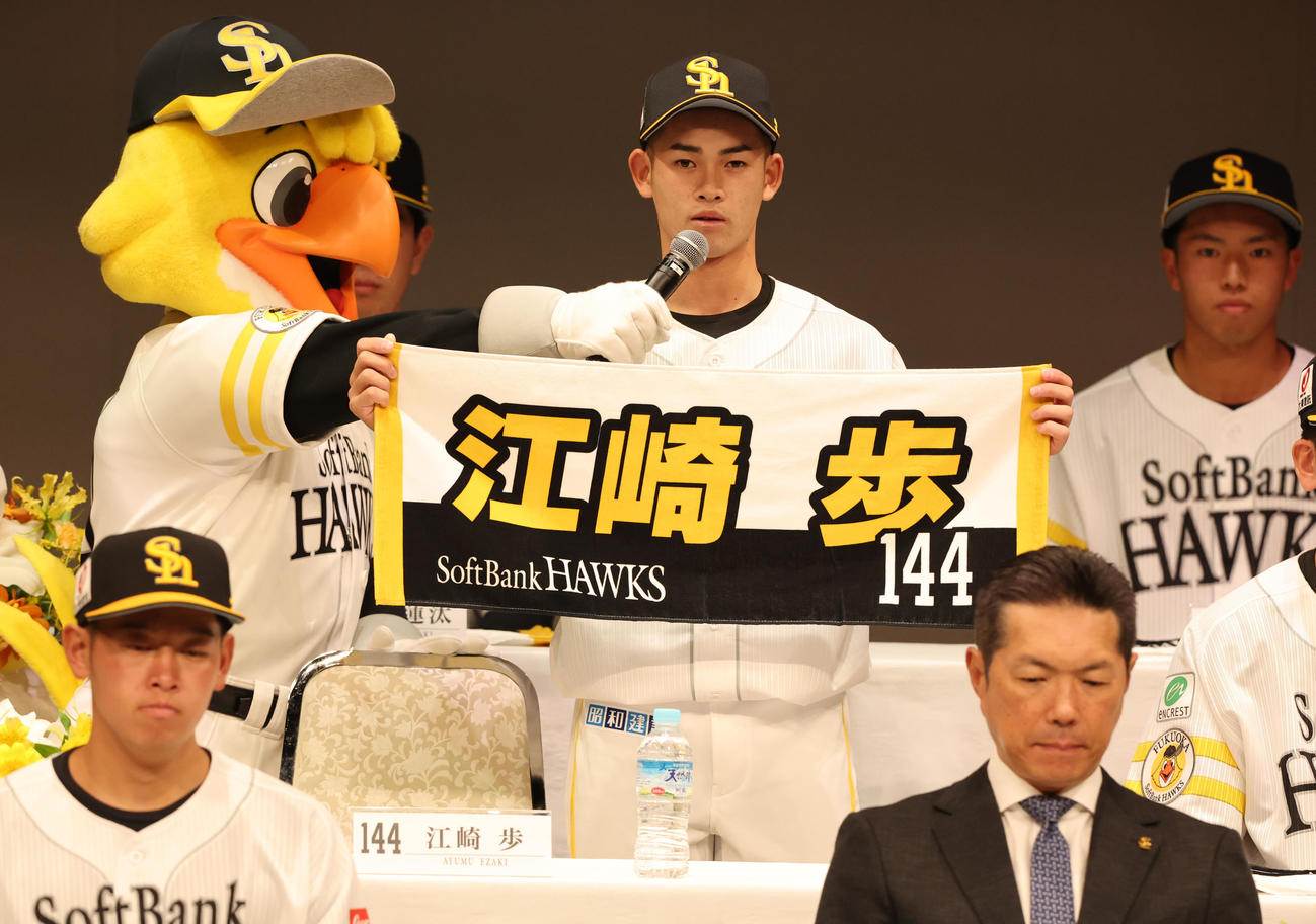 自分のネーム入りタオルを手に自己紹介をする江崎（撮影・梅根麻紀）