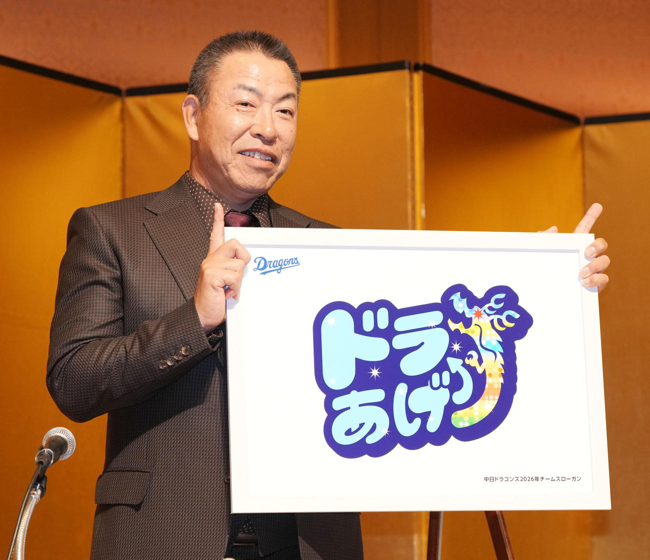 2026年スローガンのパネルを掲げる井上一樹監督（撮影・森本幸一）