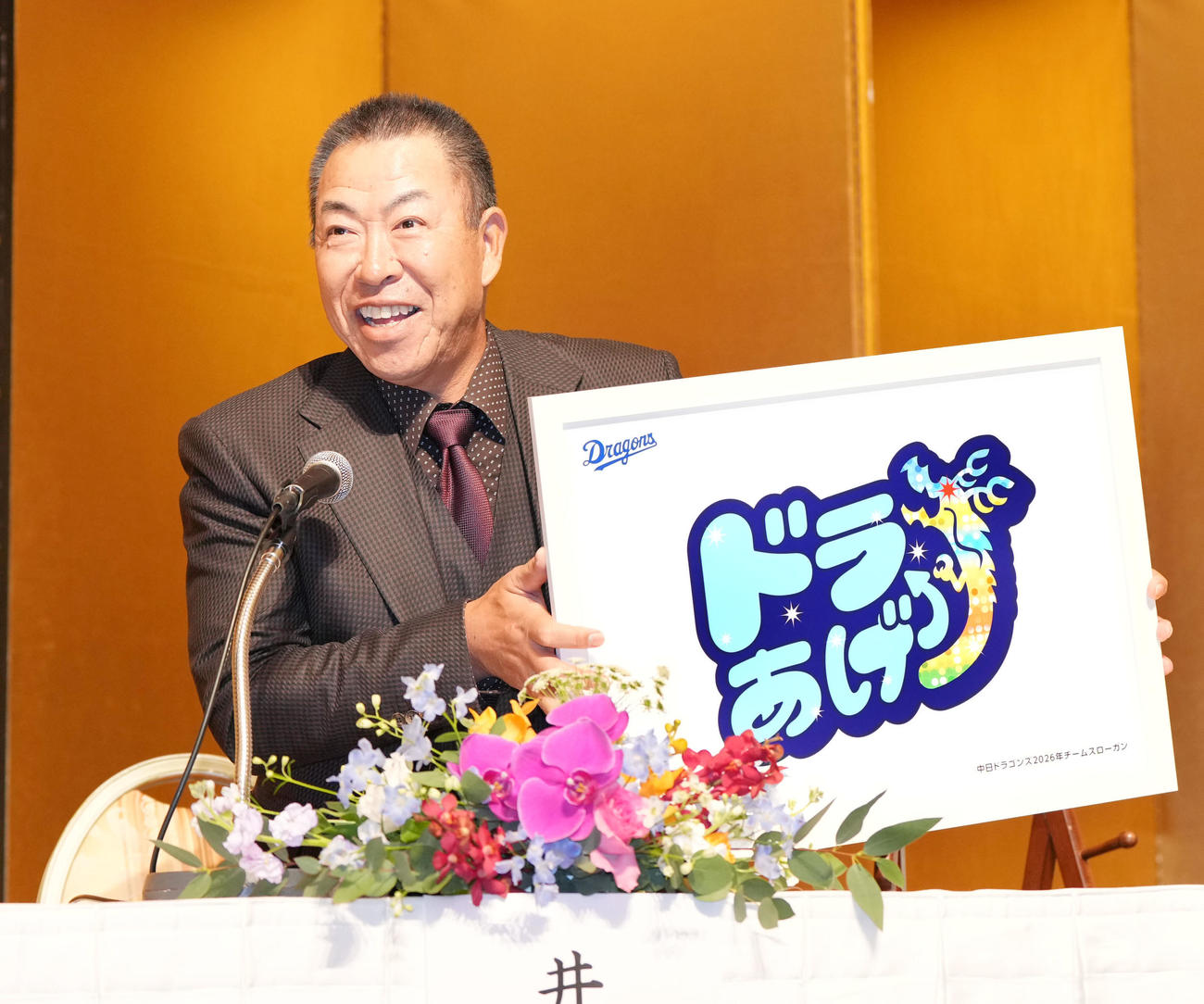 2026年スローガンのパネルを掲げる井上一樹監督（撮影・森本幸一）