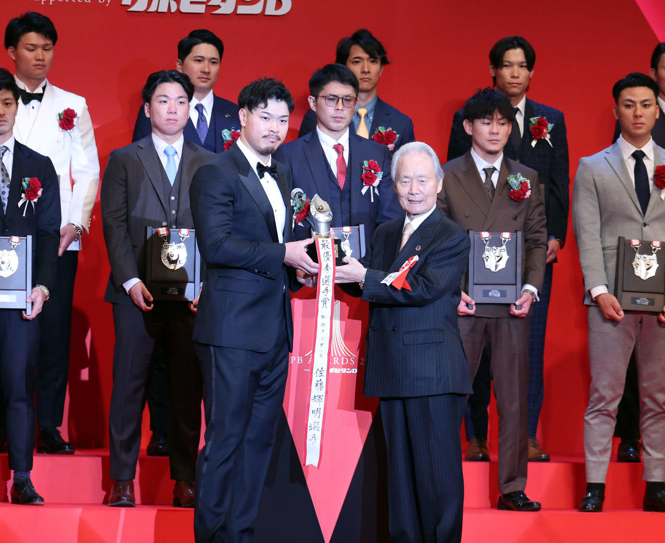 NPB AWARDS 2025　最優秀選手賞を受賞した阪神佐藤輝（左）は榊原コミッショナーからトロフィーを受け取る（2025年11月撮影）