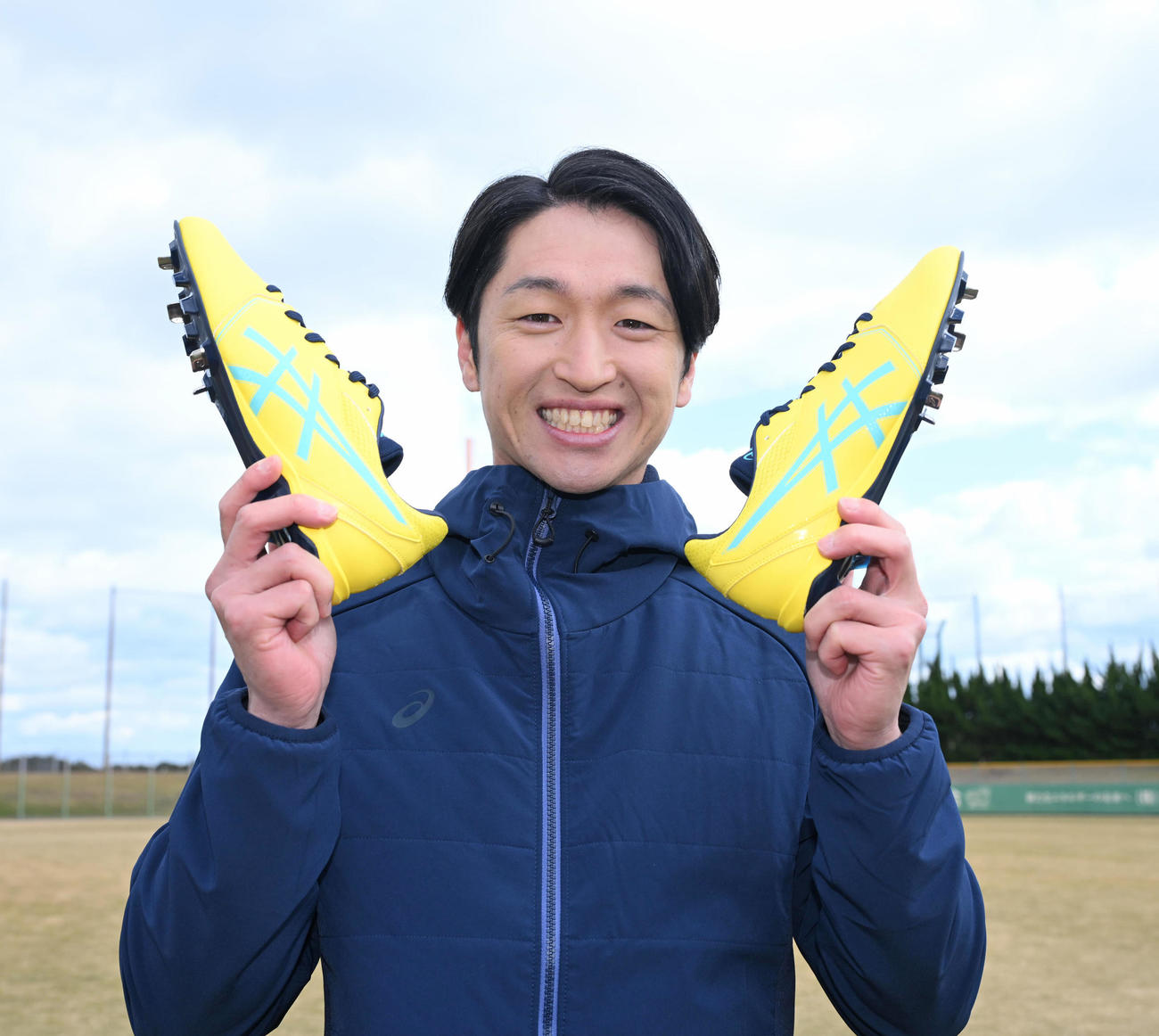 アシックスの新型スパイクを手に笑顔を見せる近本（撮影・石井愛子）